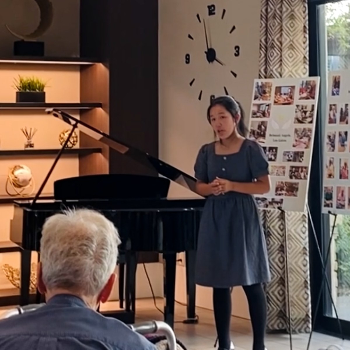 A student vocalist performing for a resident in a smaller community room.