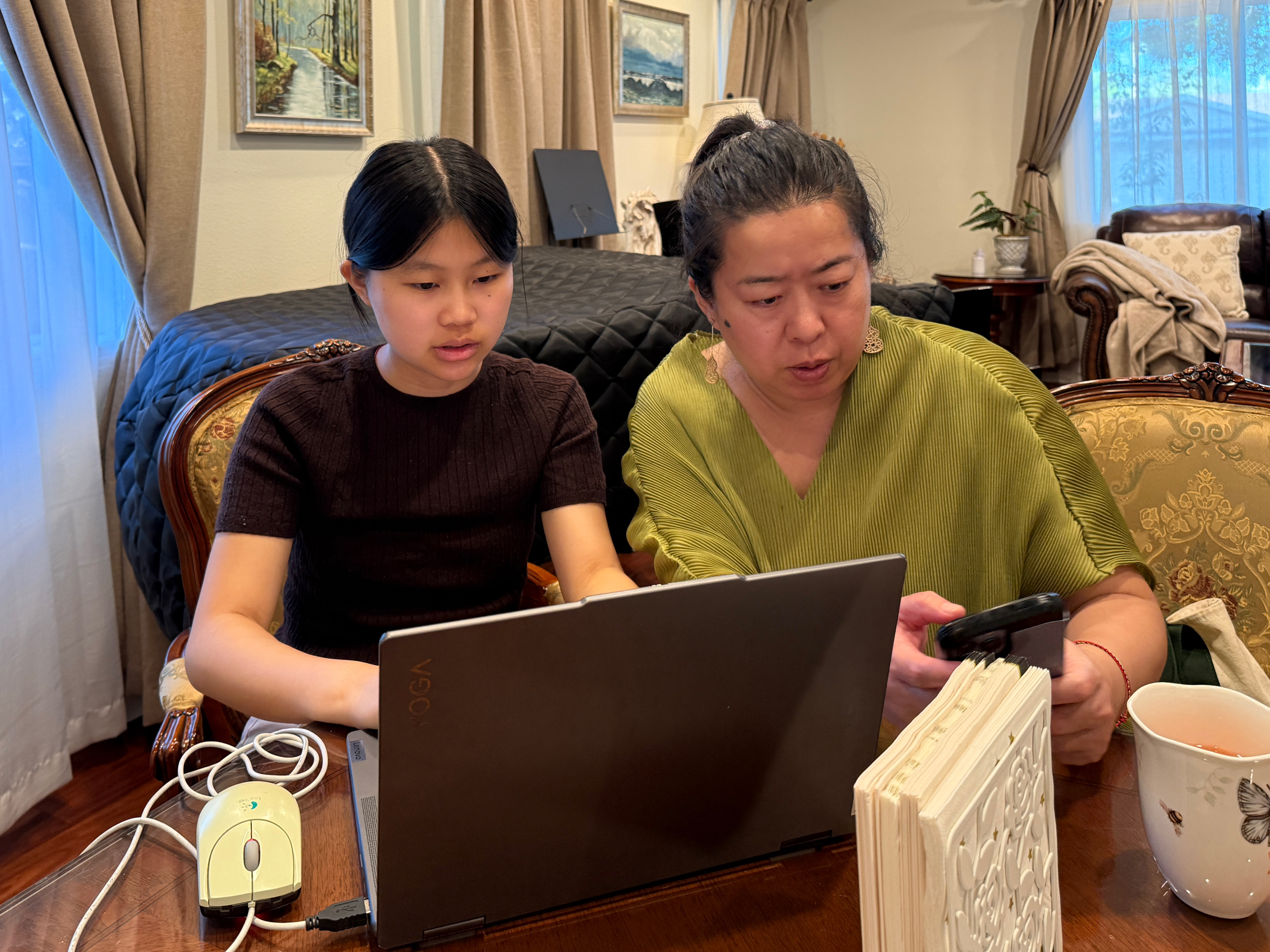 A student and advisor working together on planning materials at a laptop.